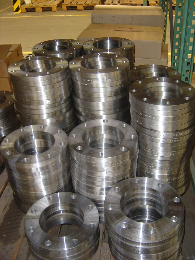 Stacked loose flanges with stamped marking running round the rim, on pallets in the warehouse