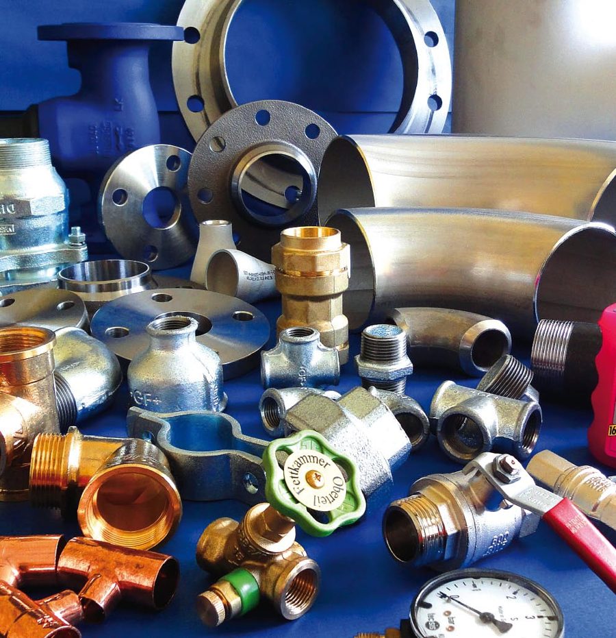 Rohrleitungsprodukte aus verschiedenen Werkstoffen: Stahlflansche, Edelstahlbogen, Messing-Kugelhähne und Manometer